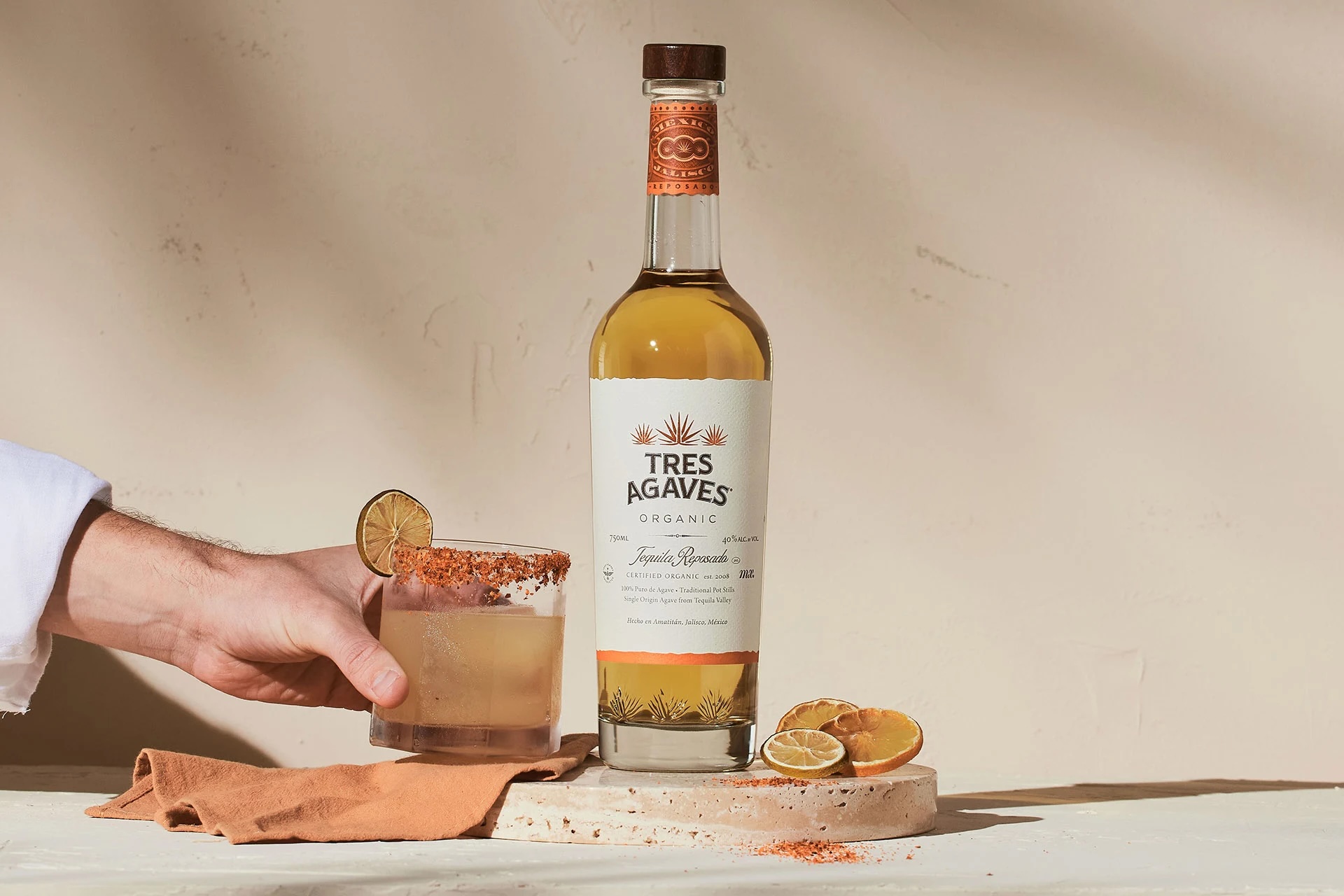 Tres Agaves Spirit Brand of the Year Award Image of a bottle of Tres Agaves Tequila with a hand holding a cocktail glass